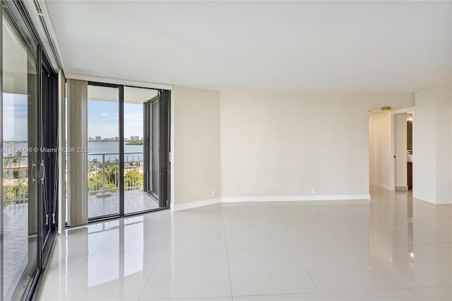 tiled empty room featuring a water view and floor to ceiling windows