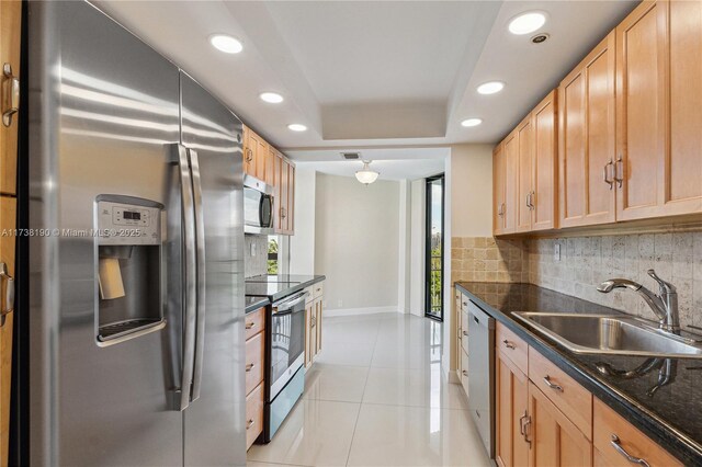 kitchen featuring appliances with stainless steel finishes, a tray ceiling, sink, and backsplash