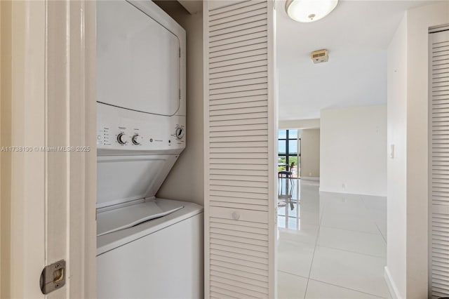 laundry room with stacked washer / drying machine and light tile patterned floors