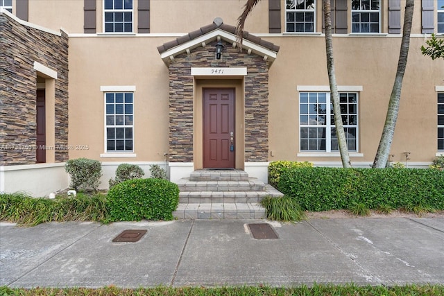 view of exterior entry featuring stone siding and stucco siding