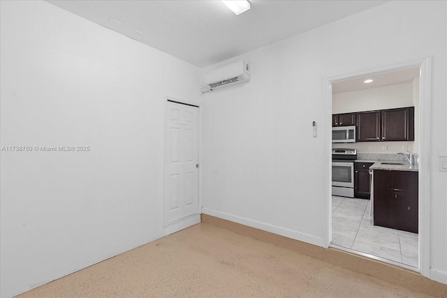 empty room with baseboards, a sink, and a wall mounted air conditioner