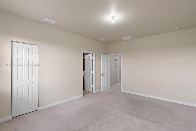 spare room featuring light carpet, visible vents, and baseboards