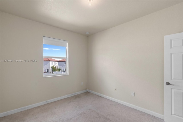 unfurnished room featuring light carpet and baseboards