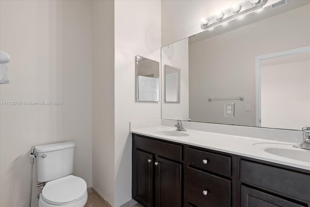 bathroom featuring toilet, double vanity, a sink, and visible vents