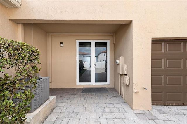 entrance to property with a garage, stucco siding, and french doors