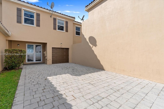 view of front facade featuring a garage, decorative driveway, and stucco siding