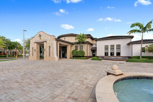 back of house with a jacuzzi, a swimming pool, a patio, and stucco siding