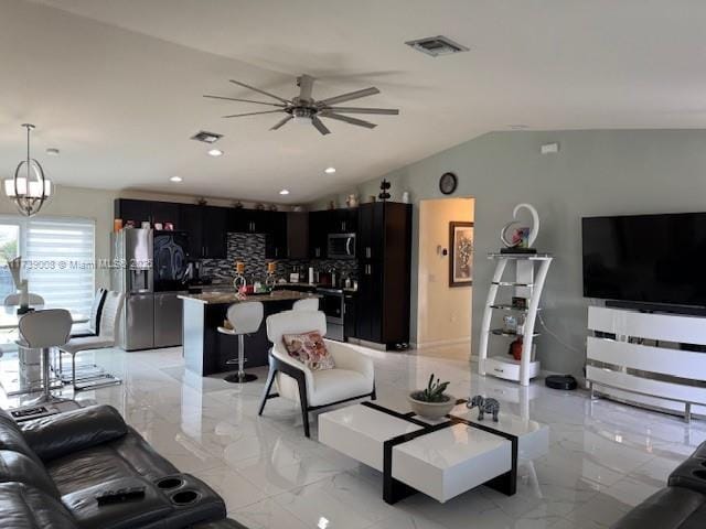 living room featuring vaulted ceiling and ceiling fan with notable chandelier