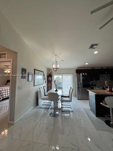 dining space with vaulted ceiling and ceiling fan with notable chandelier