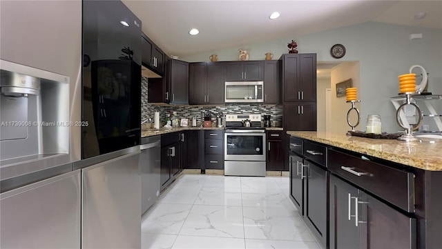 kitchen with dark brown cabinetry, vaulted ceiling, stainless steel appliances, and tasteful backsplash