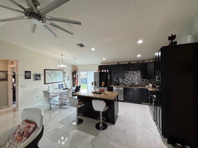 kitchen with a kitchen island, appliances with stainless steel finishes, decorative light fixtures, a breakfast bar area, and light stone counters