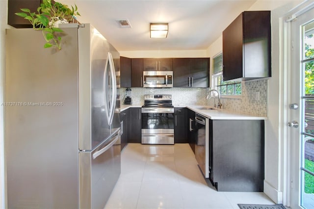 kitchen featuring appliances with stainless steel finishes, sink, dark brown cabinets, and backsplash