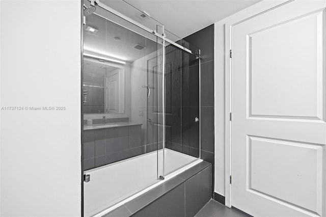 bathroom featuring bath / shower combo with glass door and sink