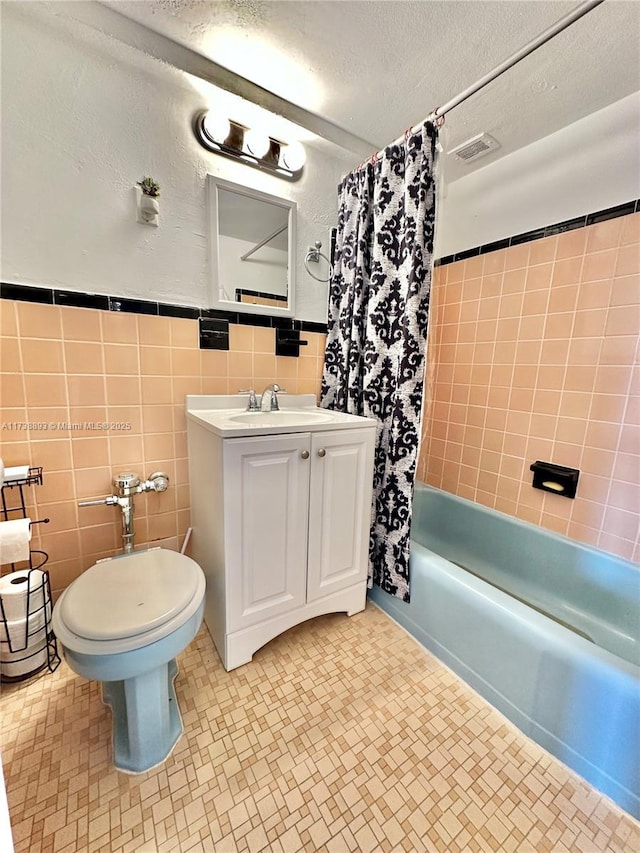 bathroom featuring tile walls, toilet, a textured ceiling, vanity, and shower / bathtub combination with curtain