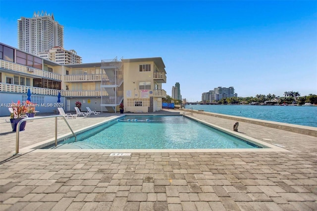 community pool featuring a view of city, a water view, and a patio area