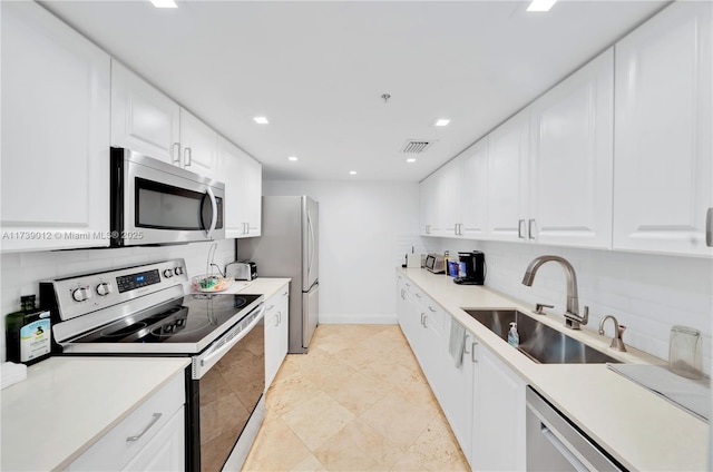 kitchen featuring stainless steel appliances, sink, white cabinets, and decorative backsplash