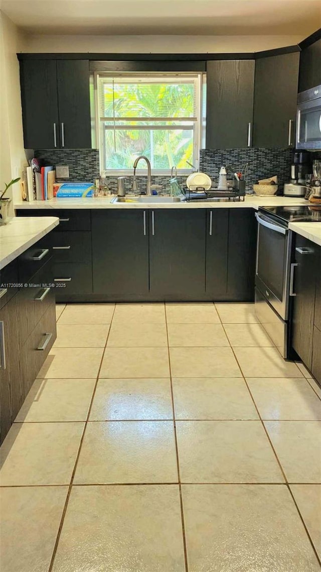 kitchen featuring tasteful backsplash, light tile patterned flooring, appliances with stainless steel finishes, and sink