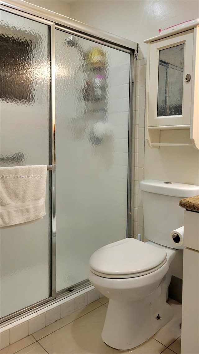 bathroom featuring tile patterned flooring, an enclosed shower, and toilet