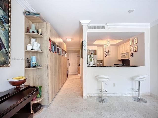 kitchen with stainless steel refrigerator, ornamental molding, and a breakfast bar