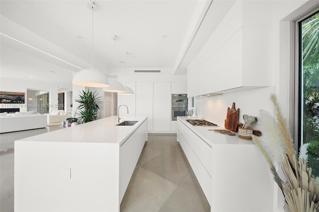 kitchen with sink, white cabinetry, appliances with stainless steel finishes, pendant lighting, and a large island