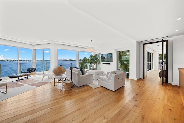 living room with a water view, lofted ceiling, and light hardwood / wood-style flooring