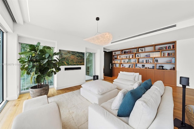 living room featuring built in shelves and light hardwood / wood-style floors