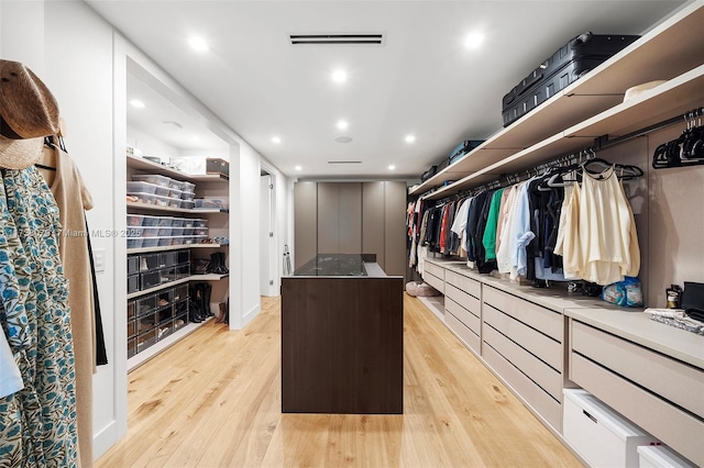 walk in closet with light hardwood / wood-style floors