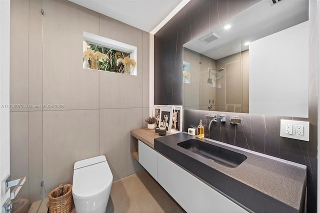 bathroom featuring walk in shower, toilet, tile walls, vanity, and decorative backsplash