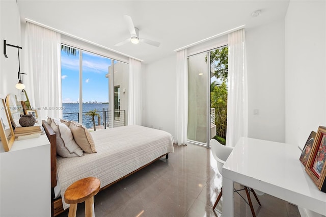 bedroom with multiple windows, access to outside, floor to ceiling windows, and a water view