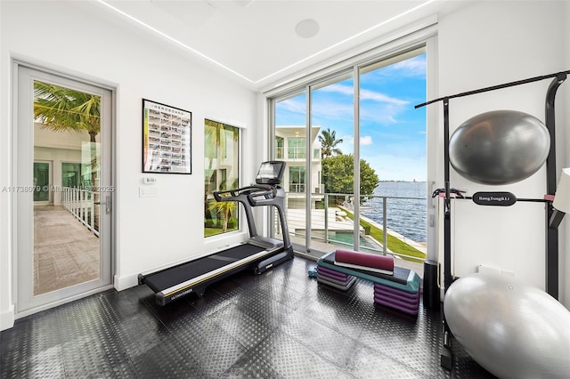 workout room with floor to ceiling windows and a water view