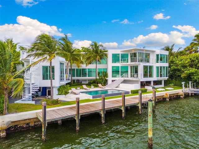 rear view of house featuring a water view, a balcony, and a patio area