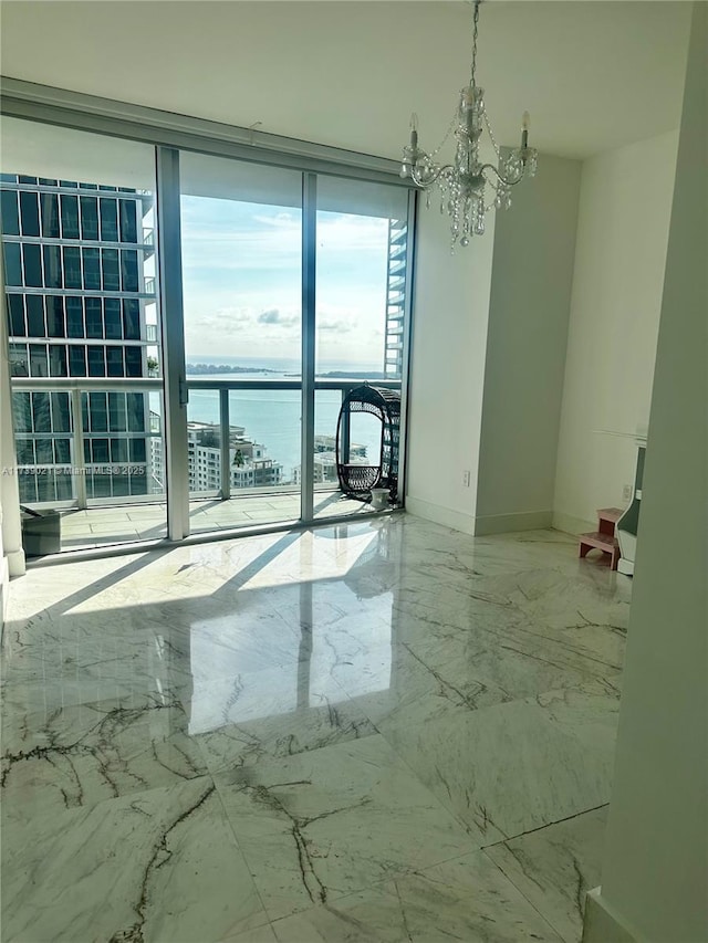 empty room with a water view, an inviting chandelier, baseboards, and marble finish floor