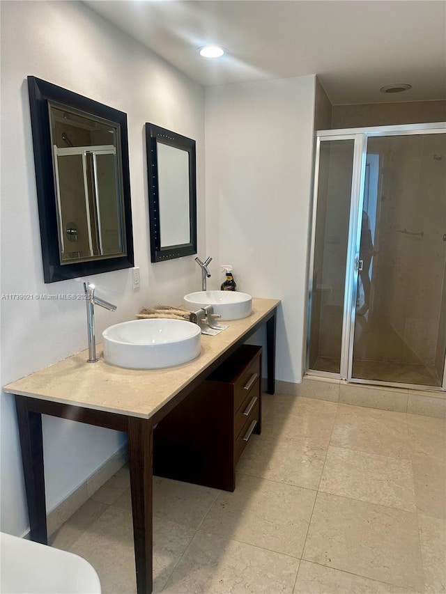bathroom with double vanity, a stall shower, a sink, and tile patterned floors