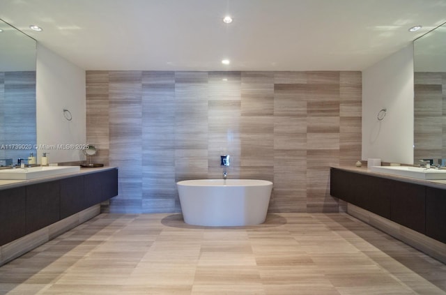 bathroom with vanity, tile patterned flooring, a bathtub, and tile walls