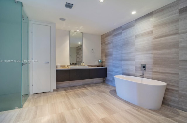 bathroom with vanity, separate shower and tub, and tile walls