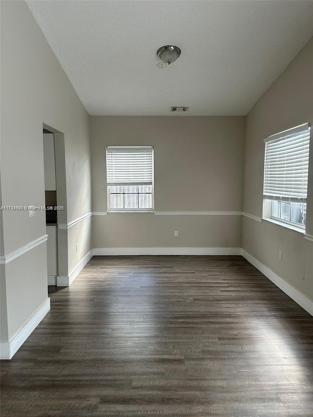 unfurnished room with dark hardwood / wood-style flooring, vaulted ceiling, and plenty of natural light