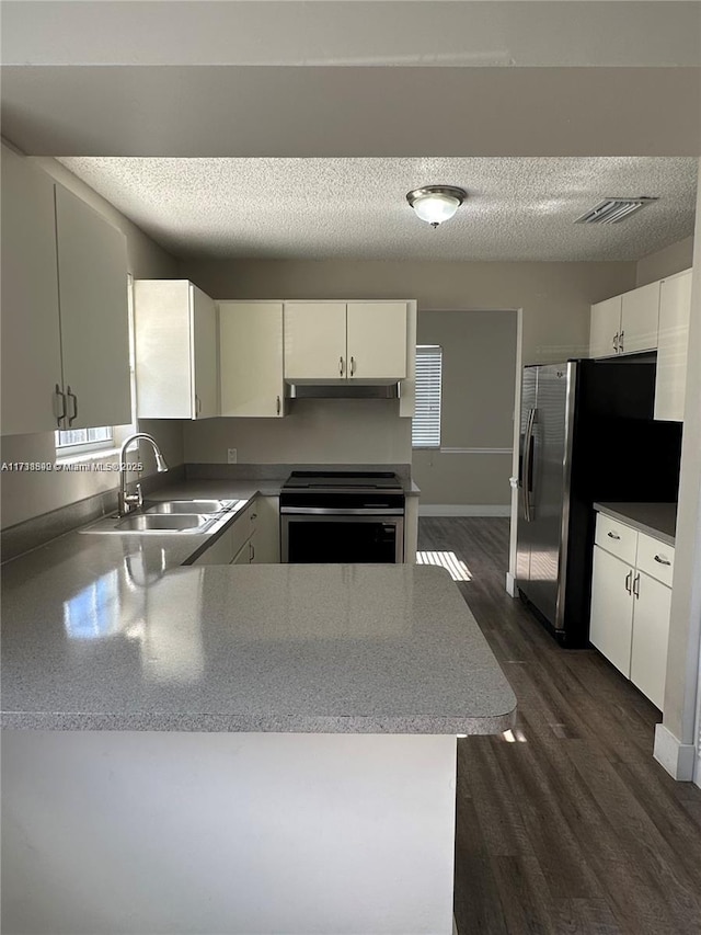 kitchen featuring sink, a textured ceiling, dark hardwood / wood-style flooring, kitchen peninsula, and stainless steel appliances