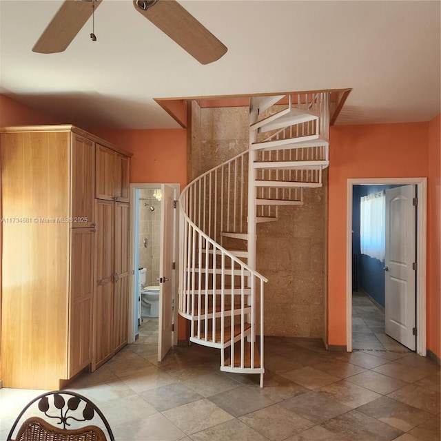 stairway featuring a ceiling fan