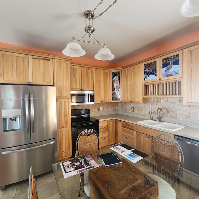kitchen with a sink, appliances with stainless steel finishes, tasteful backsplash, and glass insert cabinets