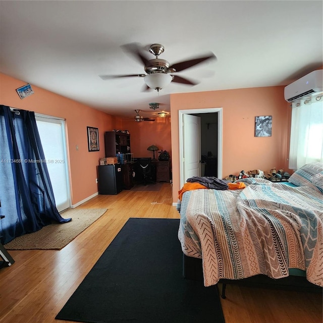 bedroom with multiple windows, a wall mounted air conditioner, ceiling fan, and light hardwood / wood-style flooring