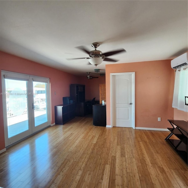 unfurnished living room featuring baseboards, a wall mounted AC, a ceiling fan, and wood finished floors
