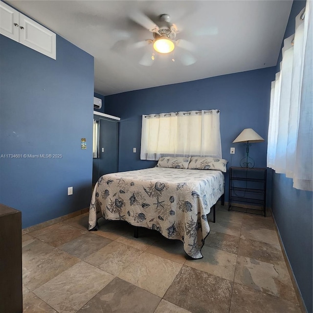 bedroom with stone tile flooring, baseboards, ceiling fan, and a closet