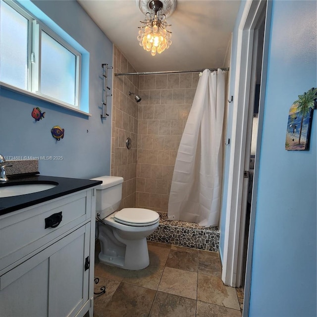 full bath featuring vanity, a stall shower, stone finish floor, and toilet