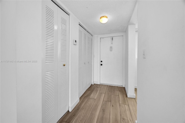 hall featuring a textured ceiling and light hardwood / wood-style flooring