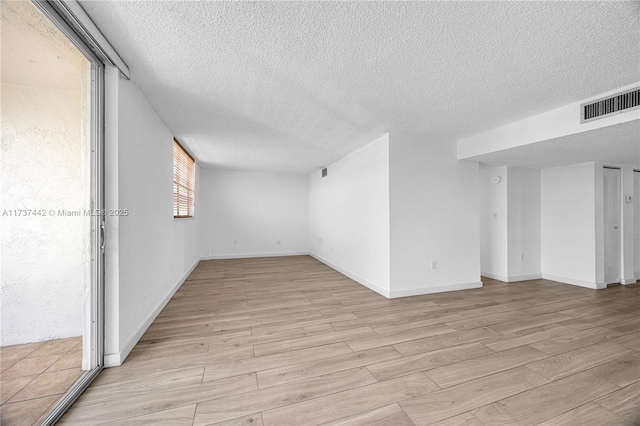 unfurnished room with a textured ceiling and light wood-type flooring