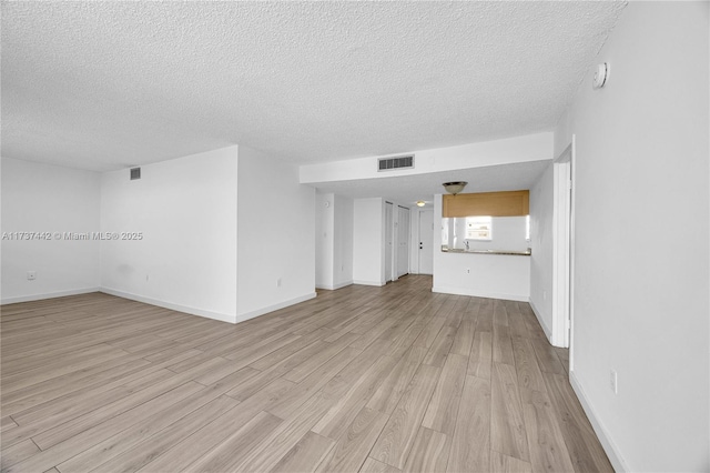 unfurnished living room featuring a textured ceiling and light hardwood / wood-style floors