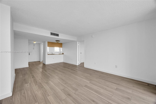 unfurnished living room featuring light hardwood / wood-style floors and a textured ceiling