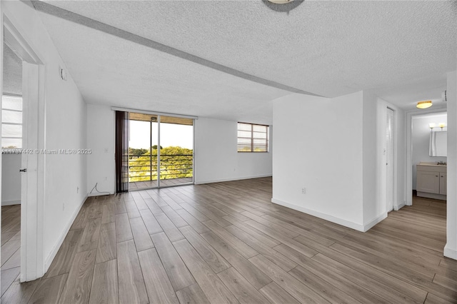 unfurnished room with light hardwood / wood-style flooring, floor to ceiling windows, and a textured ceiling