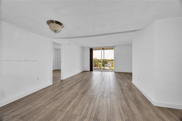 unfurnished room featuring a textured ceiling, light hardwood / wood-style floors, and a wall of windows