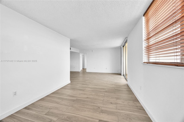 corridor with a textured ceiling and light hardwood / wood-style floors